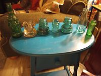 Seven vintage glass insulators and bottles displayed on blue table