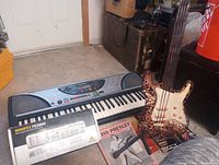 Lot overview showing keyboard, decorative guitar, Behringer box, records and stand