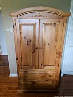 Front view of closed pine armoire showing doors and drawers