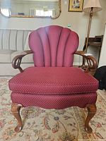 Front view of burgundy upholstered armchair showing fan-back, seat cushion, wooden arms and cabriole legs