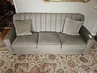Front view of grey velvet couch with two pillows