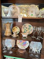 Three cabinet shelves showing all glassware and china
