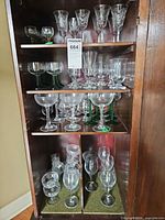 Four shelf cabinet filled with assorted stemmed glassware