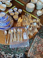 Overhead view of entire flatware lot spread on table, showing quantity and variety of pieces