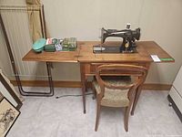 Sewing machine in cabinet with chair and accessories visible