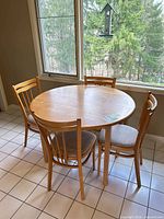 Round maple table with chairs by window