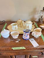 Group shot of all porcelain pieces and sterling spoons on wooden surface