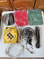 Overview of all items on table: Powermate cord reel, SnakeLight, desk fan, two packaged Rockport shoe bags