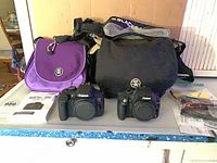 Both Canon camera bodies, Crumpler bags, BlackRapid straps, manuals, cables arranged on surface
