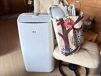 Front view of portable air conditioner beside bag holding window kit