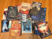 Overhead shot of assorted paperbacks fanned on floor, titles such as Colony One Mars, Buried Magic, Lailah visible