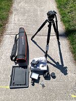 Full lot layout on sidewalk including tripod, bag, tablet tray, LED light, mic, lenses, hardware