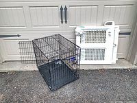 Wire dog crate and plastic gate side by side in front of garage door