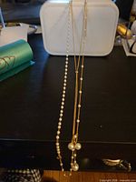 Both necklaces hanging to show full length and pearl details