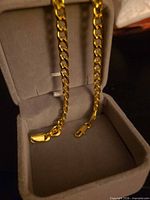 Gold-tone curb chain choker draped in grey box