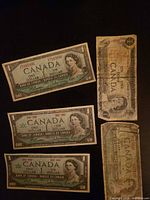 Front view of four $1 bills plus one folded bill showing obverse designs