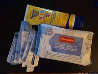 Group shot showing sunscreen tube, baby wipes pack, stack of mask sachets