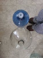 Top view of clear glass carboy opening next to reference bottle