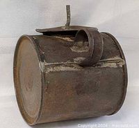 Side view of cylindrical tin oil can showing seam, top loop handle and closed lid