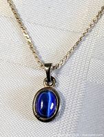 Front view close-up of pendant on sterling chain showing blue cabochon and link detail