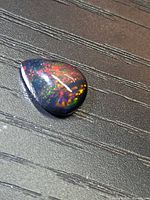 Top view of pear cabochon black opal displaying multicolour play-of-colour