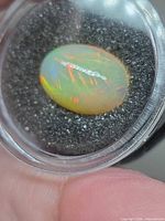 Oval opal cabochon in display case showing script pattern and colour play