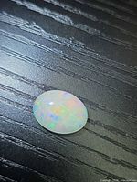 Oval cabochon opal showing play-of-color on dark background