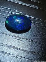 Top view of the oval black opal showing play of color