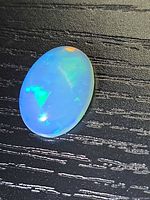 Front view of oval crystal opal cabochon showing play-of-color