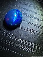 Top view of oval black opal showing body color and play-of-color