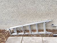 Collapsed multi-position ladder section leaning against wall