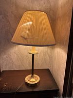 Full view of lamp with shade illuminated on tabletop