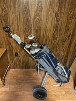 Full view of golf bag on push cart with clubs