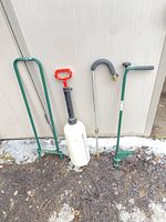 Group shot of sprayer, soil corer and rolling edger leaning against shed wall