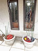 Two beige resin planters in front of wall with stakes and inserts visible