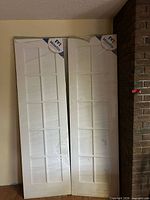 Two shrinkwrapped white French interior doors leaning against wall