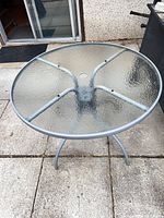 round glass patio table on concrete patio