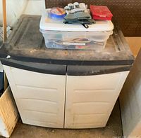 Cabinet with tote on top containing gloves, tape, red case