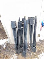 Group of seven black steel post stakes leaning against wall