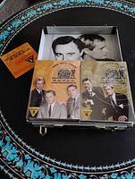 Open briefcase showing two DVD booklet cases and interior cast photo plus booklet
