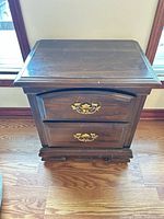 Front view of dark brown two-drawer nightstand with brass-tone pulls