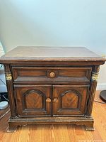 Front view showing drawer, cabinet doors, brass-tone accented columns