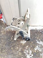 side view of beige plastic hose reel cart with partial hose and wheels