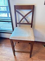 Front view of brown wood counter stool with X-back and beige seat