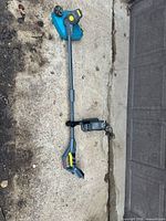 Full view of Yardworks cordless trimmer/edger with attached battery and charger beside