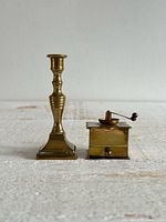 Front view of brass candlestick holder and coffee grinder miniatures