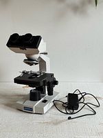 Front angled view of OMAX binocular microscope with power adapter