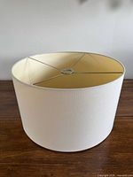 Exterior view of off-white drum lampshade on wood surface