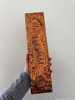 Front view of hammered copper plaque held in hand