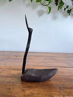 front view of carved wooden bird with long neck and simple body